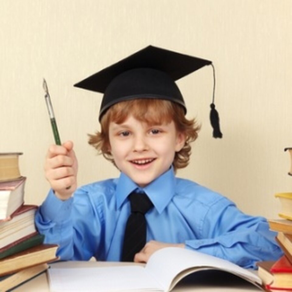 Young child in grad cap holding up fountain pen