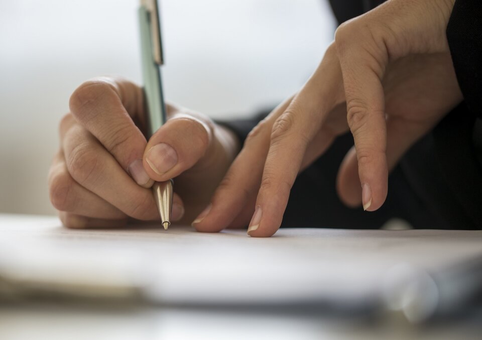 Hands holding a pen on papers